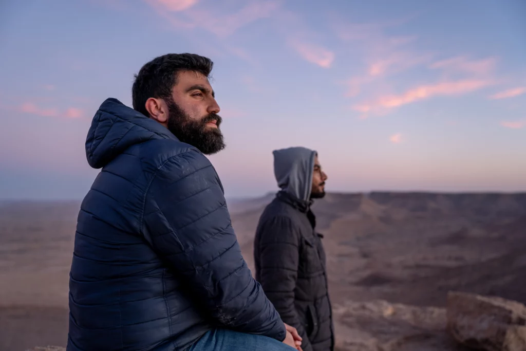 Sadok and his friend, sitting on the top of The Mountain of Guermessa in Tataouine in one of the beautiful landscapes of Tunisia in addition to Travel tips and monuments