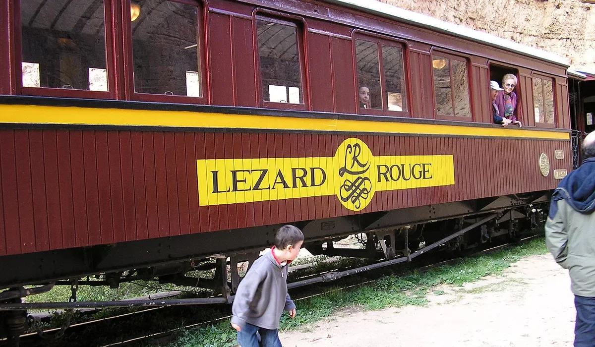 The Lezard Rouge train with its red lacquered carriages passing through the rocky Selja Gorges in Tunisia.