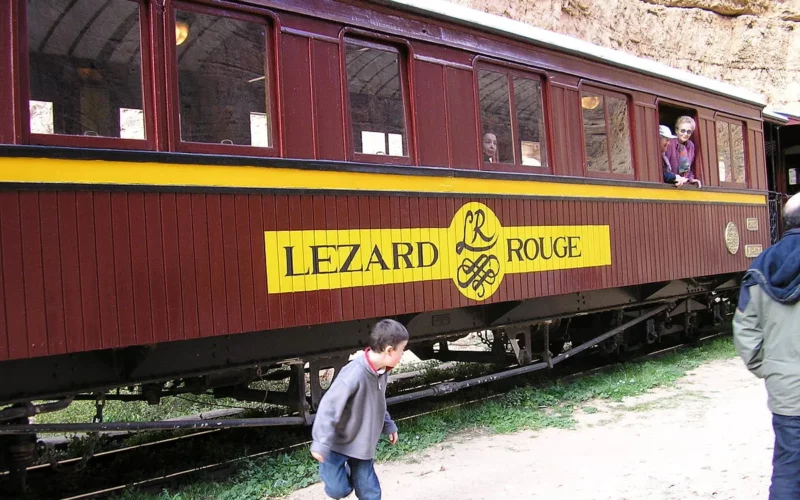The Lezard Rouge train with its red lacquered carriages passing through the rocky Selja Gorges in Tunisia.